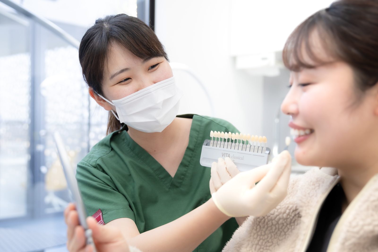 シェードガイドを当てて歯の色を比べている