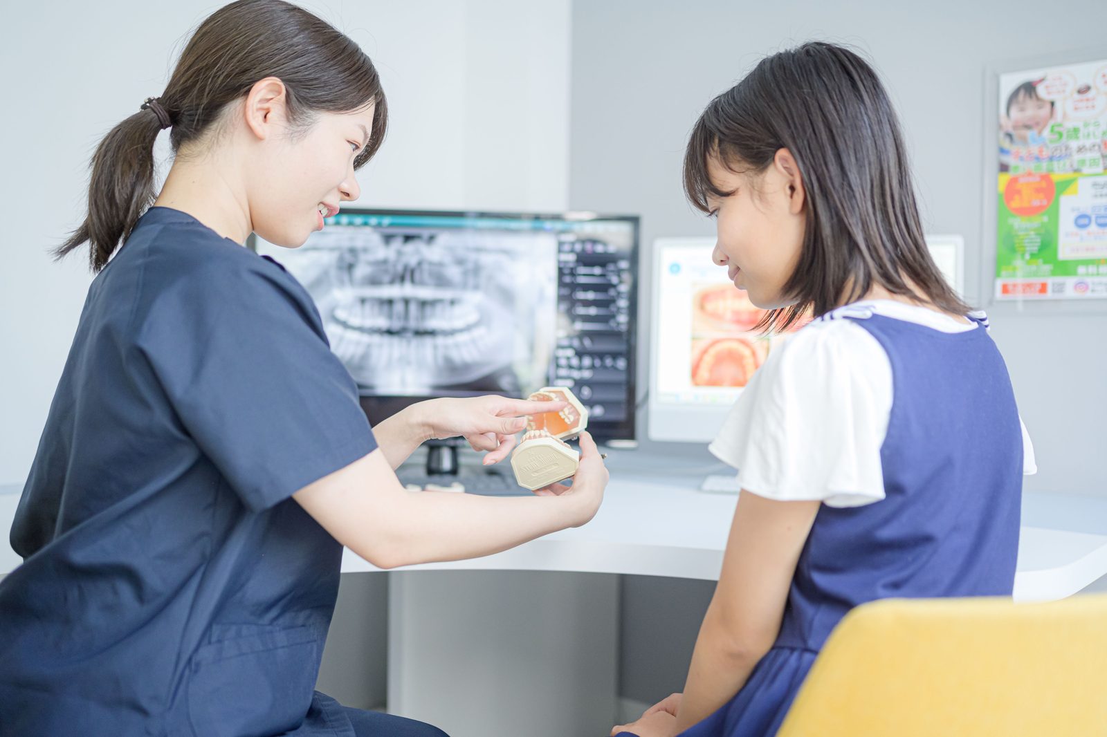 モニターのレントゲン画像を見せながら子どもに説明している