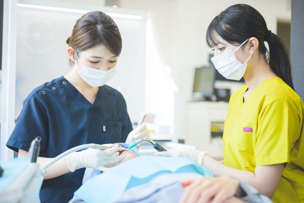 愛媛インプラントクリニックかまくら歯科にて、歯科医師がマイクロスコープ（歯科用顕微鏡）を用いて精密な治療を行っている様子。肉眼では見えない細かな虫歯や歯の根の管を確認し、インプラント治療や根管治療の精度を高めるための高度な設備を使用しています。