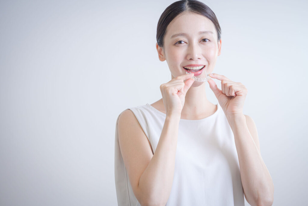 愛媛インプラントクリニックかまくら歯科で処方されたホームホワイトニング用の専用マウスピースを手に持つ女性。愛媛県松山市で自宅にいながら自然な白さを目指せる、低刺激なホワイトニングジェルの使用感や装着イメージを具体的に伝えます。