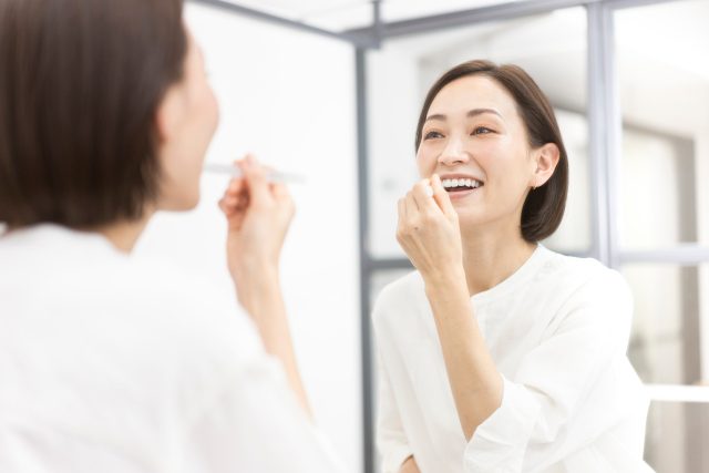 鏡の前でフロスを使う女性